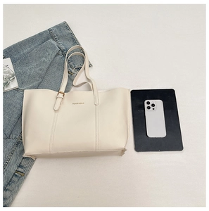 Overhead view of minimalist ivory tote bag with gadgets and denim jacket background