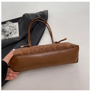 Detail view of brown leather base and leopard print suede texture on tote bag