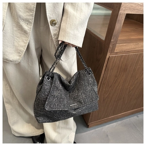 Détail du sac cabas en tweed gris avec bandoulière en chaîne et plaque métallique