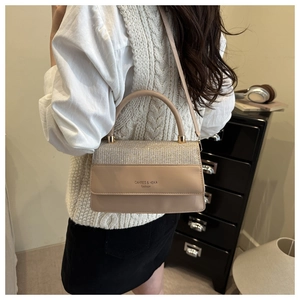 Detail view of stylish beige square bag featuring glitter patchwork and round handle