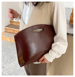 Close-up of a dark brown minimalist briefcase handbag in polished faux leather