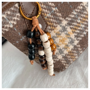 Détail d'un charme en perles de bois multicolores sur un sac cabas rétro à carreaux