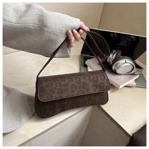 Detail of dark brown leopard print baguette bag with matte texture and adjustable strap
