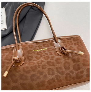 Close-up of leopard print tote bag fabric with gold logo and drawstring metal hardware