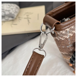Détail de la texture en tweed et de la bandoulière en cuir marron avec boucle en métal argenté