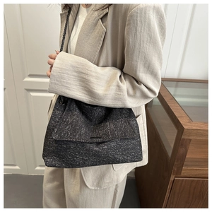 Détail du sac cabas en tweed noir avec bandoulière chaîne et texture scintillante