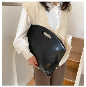 Minimalist black shiny leather tote bag with cutout handle shown in a daily lifestyle look