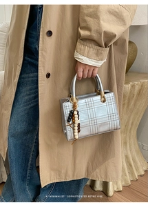 Detail of silver quilted handbag with metallic handle and decorative wooden beads