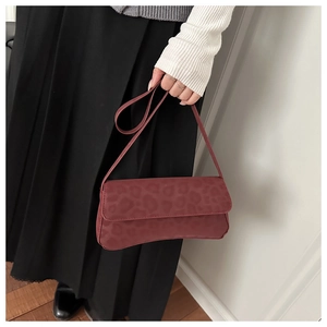 Detail of burgundy baguette bag featuring leopard texture and slim shoulder strap