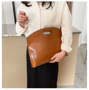 Detail of large brown PU leather handbag featuring a sleek integrated handle and smooth texture