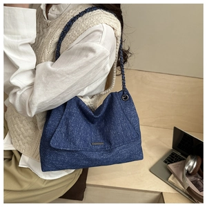 Gros plan du sac cabas en jean bleu avec bandoulière chaîne et décor de bureau