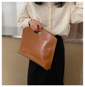 Close-up of caramel brown PU leather tote bag with cutout handle and minimalist stitching