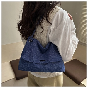 Détail d'un sac cabas en denim bleu foncé avec bandoulière chaîne porté par un mannequin