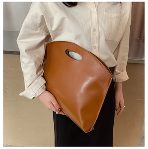 Close-up of minimalist brown oil skin handbag with unique hollowed oval handle