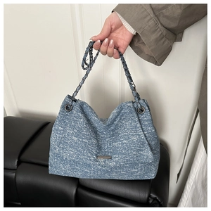 Détail du sac cabas tissé bleu et blanc avec bandoulière en chaîne et texture de luxe