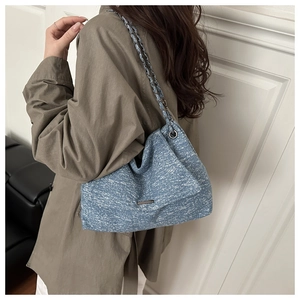 Détail du sac cabas bleu texturé avec bandoulière en chaîne argentée et plaque logo en métal