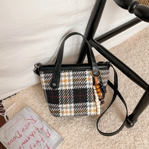 Sac cabas en tweed à carreaux avec anses en cuir et breloque en bois sur tapis doux