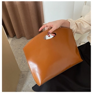 Detail of caramel brown leather handbag with unique oval cutout handle design