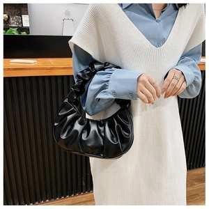 Dettaglio di una borsa a nuvola nera plissettata indossata da una modella in stile lifestyle