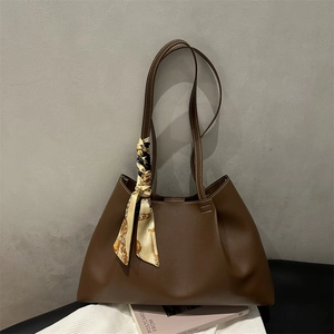 Sac fourre-tout en cuir marron avec foulard en soie décoratif sur fond tricoté
