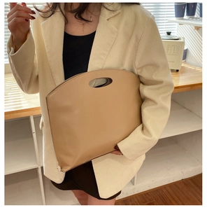 Close-up of a large minimalist apricot tote bag with an oval cutout handle for business