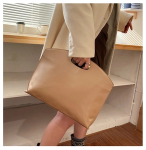 Detail of minimalist beige faux leather briefcase featuring a semicircular cutout handle