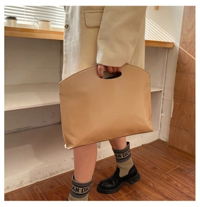 Chic beige faux leather envelope clutch bag with cutout handle held by a model