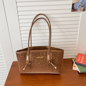 Brown leopard print tote bag with gold lettering shown in a stylish minimalist setting