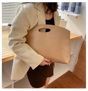Close-up of minimalist camel faux leather clutch with oval cutout handle for women