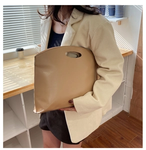 Detail of a minimalist beige leather handbag with a unique circular cutout handle