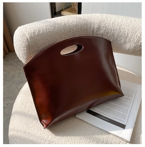 Close-up of deep red-brown leather handbag showing minimalist design and smooth texture