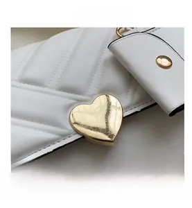 Close-up of heart-shaped gold lock on white quilted leather shoulder bag details