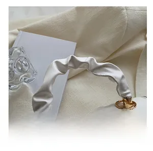 Detail of white quilted handbag featuring a soft ruched handle and golden metal ring hardware