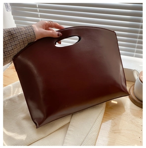 Detail of the minimalist dark brown leather tote bag with unique curved integrated handle