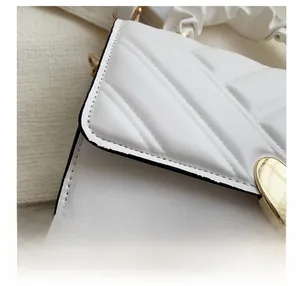 Close-up of white quilted PU leather handbag with V-stitch details and golden metal buckle