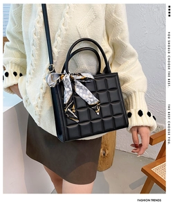 Détail du sac carré noir gaufré avec un élégant foulard en soie sur la poignée
