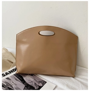 Detailed side view of caramel leather handbag featuring unique circular cutout handle