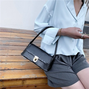 Detail of black crocodile texture shoulder bag with elegant gold metallic clasp