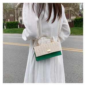 Sac bandoulière en paille beige et vert porté avec une robe d'été blanche