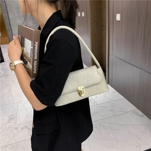 Detail of off-white crocodile embossed leather shoulder bag with gold metal lock closure