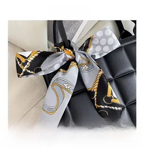 Détail d'un sac à main matelassé noir avec une poignée décorée d'un foulard en soie imprimé