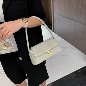 Detail of cream faux crocodile leather shoulder bag with gold metal buckle closure