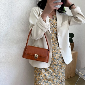 Detailed view of a brown faux crocodile leather shoulder bag with a gold metal clasp