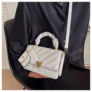 Detail of white quilted handbag with gold heart buckle and matching small coin purse