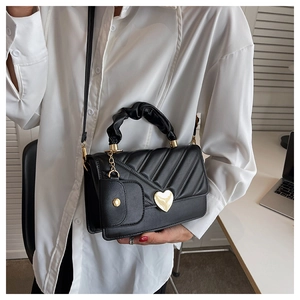 Detail of black quilted handbag with gold heart buckle and pleated ring handle