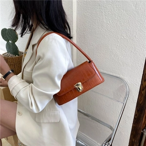 Detail of caramel brown croc-embossed shoulder bag with elegant gold metal clasp