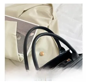 Détail du sac à main noir matelassé avec un élégant foulard en soie à pois sur l'anse