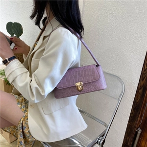 Detail of purple croc-embossed underarm bag featuring a stylish gold metal clasp