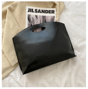 Close-up of minimalist black matte leather tote with unique oval cut-out handle detail