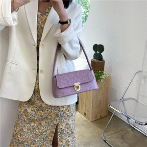 Detail view of purple crocodile texture shoulder bag with golden round metal clasp closure